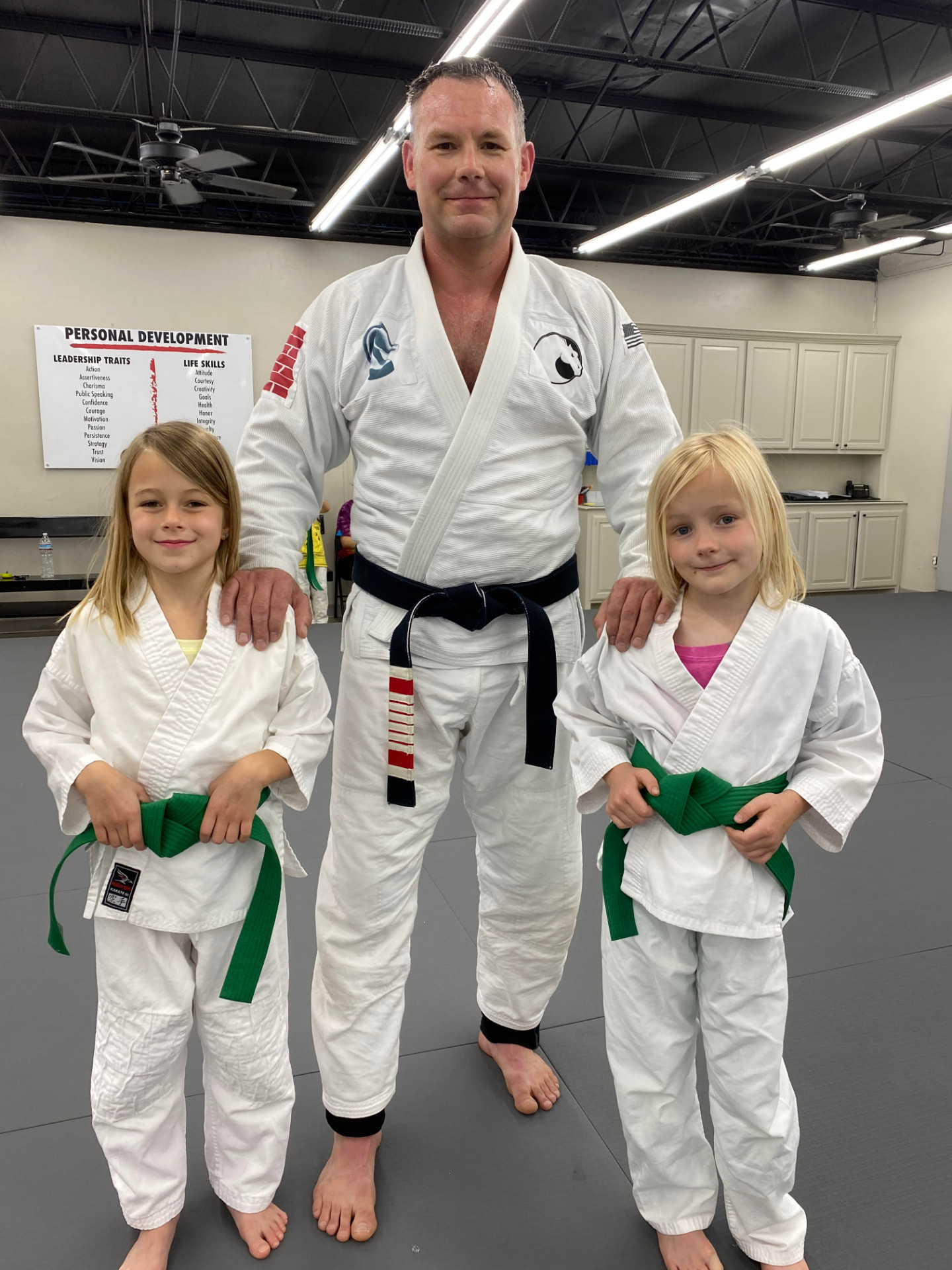 Master Klay Pittman on the mat with his two young daughters in their gis and green belts
