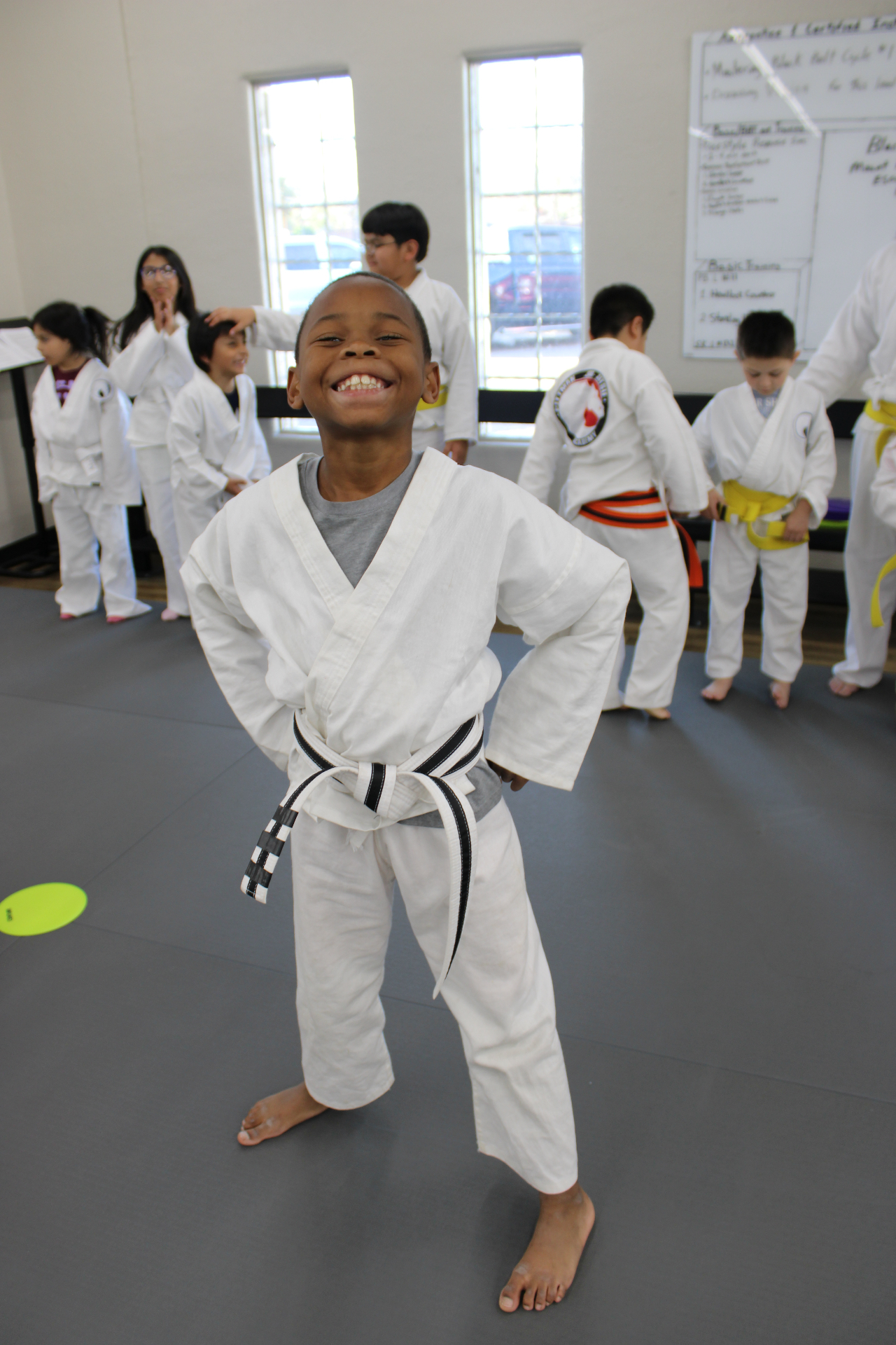 A smiling young student standing proud on the mat at Lubbock Academy of Kids Martial Arts